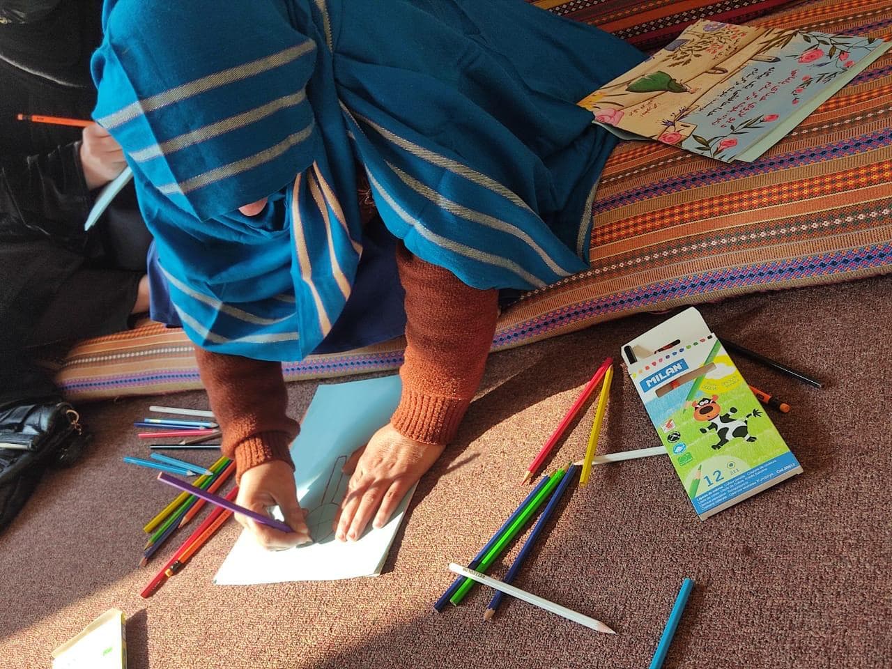An Afghan girl drawing with coloured pencils